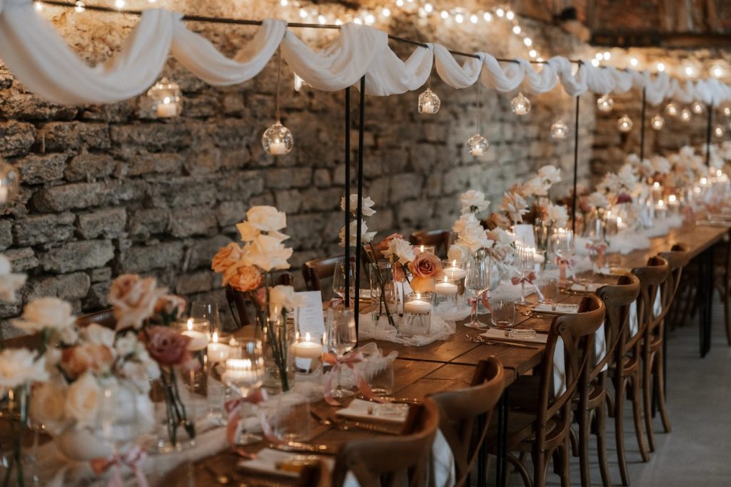 Lange Tafel in der Hofscheune mit Lichterketten und Deko in Rosa und Creme