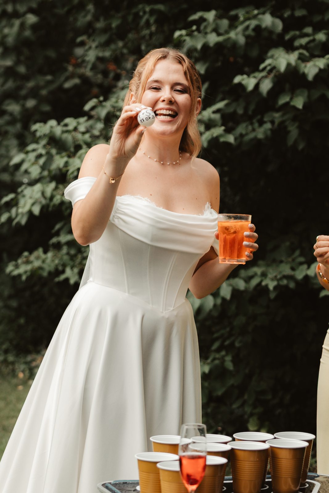 Braut spielt im Hochzeitskleid Bierpong